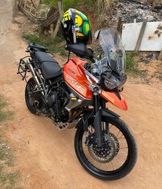 an orange motorcycle parked on top of a dirt road