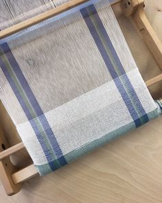 a weaving machine with blue and white plaid on the front, sitting on a wooden table