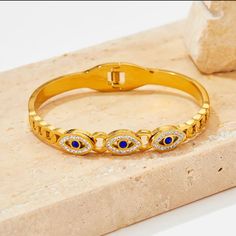 🧿 Turkish Elegance: Embrace the charm and protection of the Turkish Evil Eye with our stainless steel bangle, exquisitely crafted for a touch of cultural sophistication. ✨ 14K Gold Plated Brilliance: Adorned with a luxurious 14K gold-plated finish, this bangle radiates opulence while showcasing the timeless appeal of Turkish design. 🌈 Stainless Steel Durability: Crafted from high-quality stainless steel, this bangle offers not only elegance but also long-lasting durability for everyday wear. ? Gold Evil Eye Bangle Bracelet As Gift, Stainless Steel Tarnish Resistant Bangle For Gift, Gold Metal Evil Eye Bracelet As Gift, Gold Metal Evil Eye Bracelet For Gift, Metal Evil Eye Bangle Bracelet Gift, Pave Bangle, Stainless Steel Bangles, Blue Evil Eye, Gold Bangle Bracelet