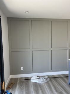 an empty room with gray walls and wood flooring in the process of remodeling