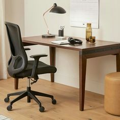 a desk with a chair, lamp and phone on it