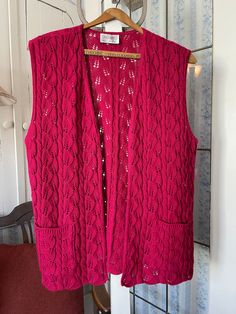 This lovely knit vest from D'Allaird's is a beautiful shade of dark raspberry pink. It's made from a wool blend and features the cable stitch, as well as open pointelle designs. It has an open front with no buttons and two front pockets. The measurements, taken with the vest lying flat, are: shoulder to shoulder, 16 inches; armpit to armpit, 19 inches; length, 27 inches; bottom edge, 24 inches. In very good condition. Fitted Pink Sweater Vest For Fall, Pink Knitted Sweater Vest For Winter, Pink Knit Vest For Fall, Fitted Pink Vest For Fall, Pink Knit Vest, Pink Sweater Vest, Vest With Pockets, Pink Vest, Pointelle Knit