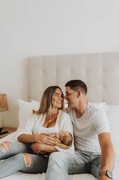 a man and woman sitting on top of a bed holding a baby