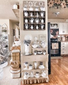 a kitchen filled with lots of white dishes and cups on top of a wooden table