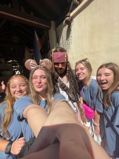 a group of young women standing next to each other in front of a man dressed as a pirate