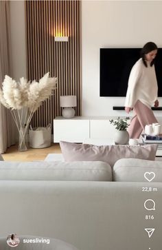 a woman in white shirt sitting on top of a couch next to a tv monitor