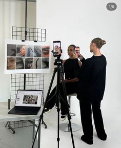 two people are taking pictures in front of a laptop and camera on a tripod