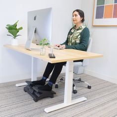 a woman sitting at a computer desk with her feet up on the keyboard and monitor