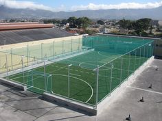 an empty soccer field in the middle of a city with mountains in the back ground