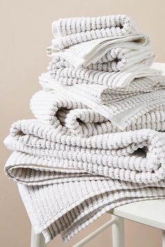 a stack of folded towels sitting on top of a white chair