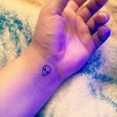 a small heart tattoo on the wrist is shown in purple hued light, and it appears to be tiny