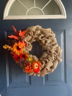 a burlock wreath with fall flowers on the front door