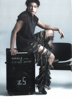 a man sitting on top of a chair next to an amp with chains around his legs