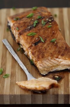 a piece of fish sitting on top of a wooden cutting board next to a knife