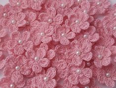 pink crocheted flowers and pearls on a white background