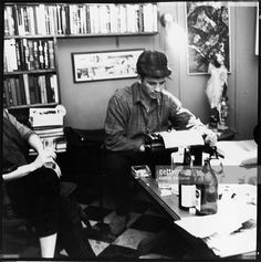 two people sitting at a table with bottles of wine and papers in front of them