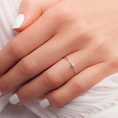 a woman's hand with a diamond ring on her left hand and white nails