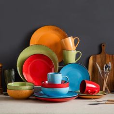 a table topped with lots of different colored plates and bowls on top of each other