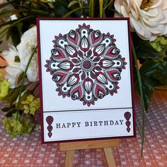 a happy birthday card sitting on top of a wooden easel with flowers in the background