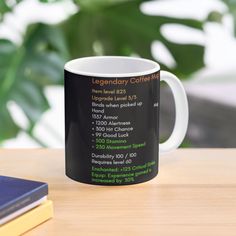 a coffee mug sitting on top of a wooden table next to a book and plant