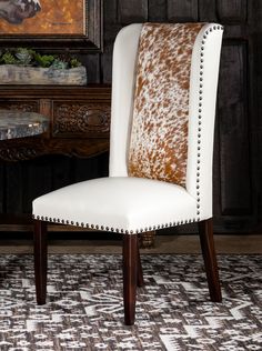 a white and brown chair sitting on top of a rug next to a wooden table