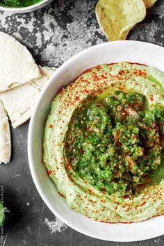 a white bowl filled with guacamole next to tortilla chips and salsa