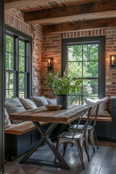 a dining room table and chairs in front of a brick wall with windows that look out onto the woods