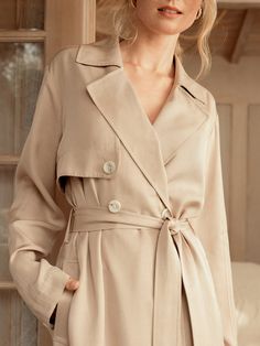 If there ever was a perfect lightweight trench, this is it. Made of a luxurious and flowy fabric, it's a stunning layering piece and can also be worn buttoned up as a dress. The color lies beautifully between beige and tan, providing a soft neutral tone that goes with literally anything in your closet, including all of our capsule pieces. With a tie belt, beautiful horn style buttons, lovely pleats, side slits and a back flap, its intentional design is what sets us apart. Whatever you pair this Elegant Single Breasted Outerwear For Day Out, Elegant Single-breasted Outerwear For Day Out, Elegant Outerwear With Lapel Collar For Day Out, Timeless Belted Outerwear For Spring, Beige Dress With Belted Cuffs For Spring, Beige Fall Dress With Belted Cuffs, Beige Spring Dresses With Belted Cuffs, Beige Long Sleeve Dress With Belted Cuffs, Beige Spring Dress With Belted Cuffs