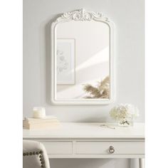 a white desk with a mirror and flowers on it