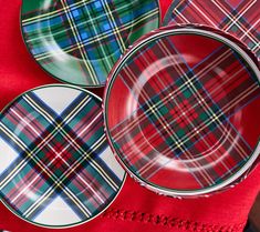 three plaid plates sitting on top of a red table cloth next to a plate with a green and blue design