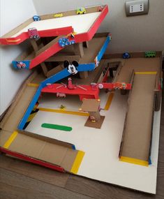 a cardboard model of mickey mouse's house with cars and trucks on the floor