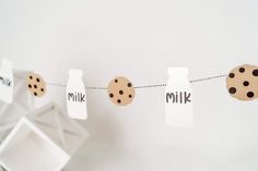 some cookies and milk are hanging on a line with clothes pins that read milk and milk