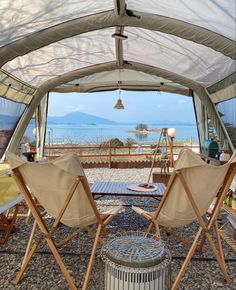 there are two chairs and an umbrella on the ground in front of a table under a tent