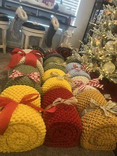 many knitted bags are stacked next to a christmas tree