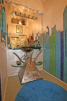 a bathroom with blue and green tiles on the walls, flooring and rugs