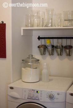 a white washer sitting next to a dryer in a kitchen under a shelf