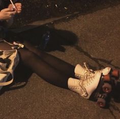 a woman sitting on the ground with her legs crossed while she is holding a skateboard