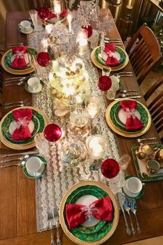 the table is set with red and green plates, silverware, and napkins