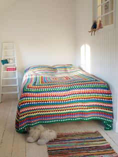 a bedroom with a bed and rugs on the floor next to a ladder in the wall