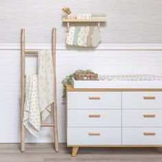 a baby crib next to a white dresser and shelving unit