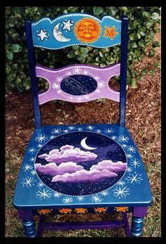 a blue chair with an image of the moon and stars painted on it's back