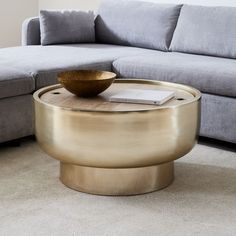 a coffee table with a bowl on it in front of a couch and rugs