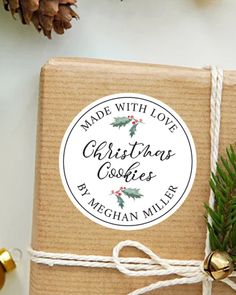 a wrapped christmas cookie box next to some pine cones and twine on a table