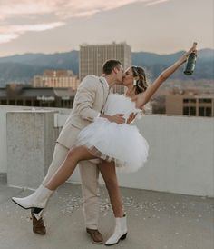 a man and woman dressed in white posing for a photo on top of a building