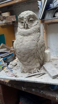 an owl statue sitting on top of a workbench in a workshop with lots of tools