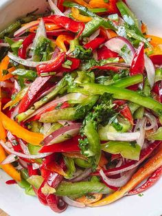 a white bowl filled with assorted vegetables on top of a wooden table