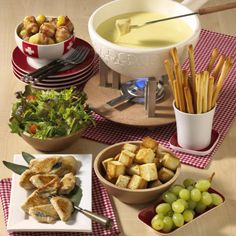 a table topped with plates and bowls filled with food next to breadsticks, salad