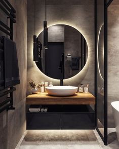 a bathroom with a round mirror above the sink and a wooden counter in front of it