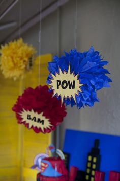 some decorations are hanging from the ceiling with pow words on them and red, white, and blue pom - poms