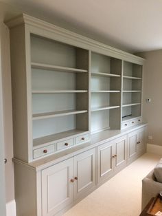 an empty living room with white bookcases and couch